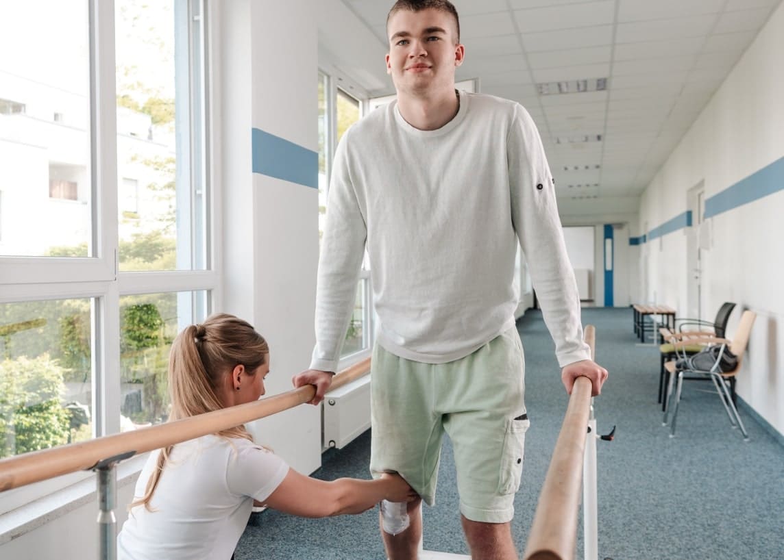 A young man walking as physical therapy with assistance from an expert